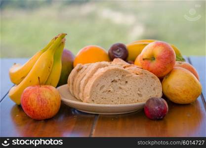 variety of fruits and bread on table in the garden
