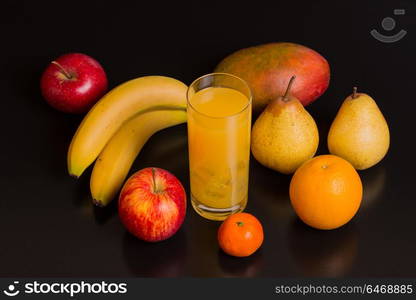 variety of fruits and orange juice on a black background, studio picture