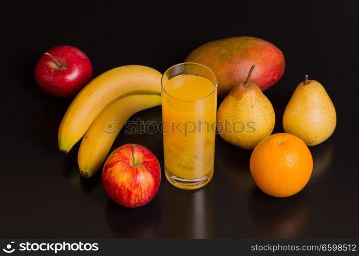 variety of fruits and orange juice on a black background, studio picture