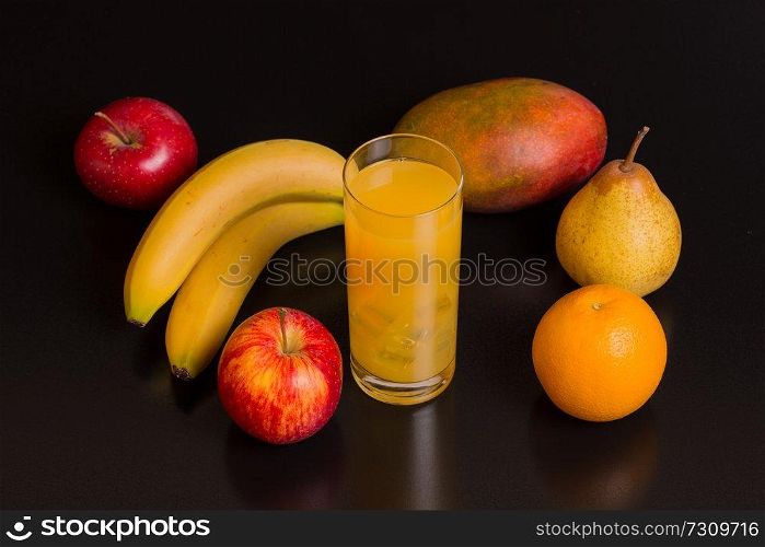 variety of fruits and orange juice on a black background, studio picture