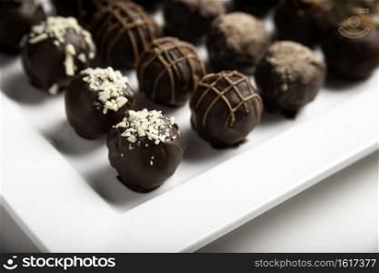 variety of handmade gourmet chocolate truffle candy on a white plate
