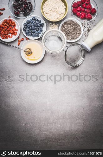 Variety of healthy breakfast ingredients on stone background, top view, border