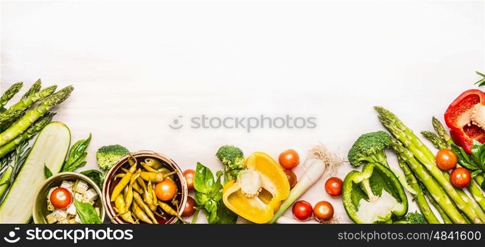 Variety of organic vegetables ingredients with asparagus and feta for delicious seasonal cooking , white wooden background, top view, place for text, banner