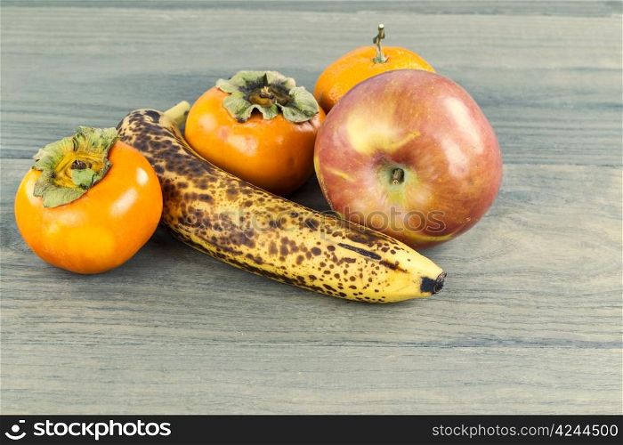 Variety of ripe fruit on faded wooden table