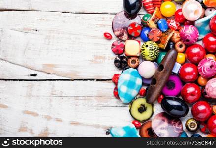 Variety of shapes and colors to make a bead necklace. Colorful beads on wooden surface