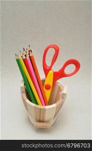 Variety of stationary in a wooden bucket against a colorful background