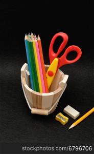 Variety of stationary in a wooden bucket against a colorful background
