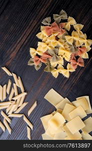 variety of types and shape of italian pasta on dark wooden table. dry pasta background