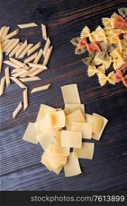 variety of types and shape of italian pasta on dark wooden table. dry pasta background