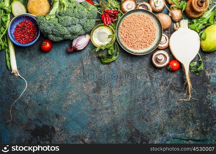 variety of vegetables, red lentil and ingredients for healthy cooking on rustic background, top view, horizontal border. Vegan food or diet eating concept.