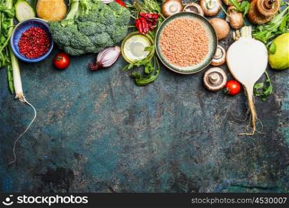 variety of vegetables, red lentil and ingredients for healthy cooking on rustic background, top view, horizontal border. Vegan food or diet eating concept.