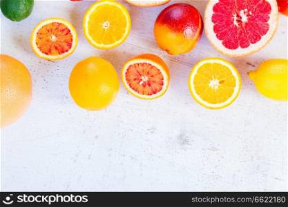 Variety of whole an cut oranges with copy space on white wooden table. Variety of citruses