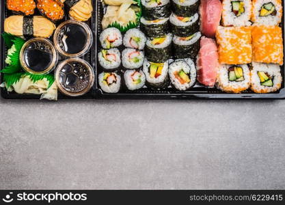 Variety Sushi : rolls, nigiri, maki, out rolls and inside rolls on gray stone background, top view, horizontal border. Japanese and Asian food.