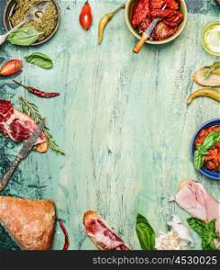 various antipasti with ciabatta bread, pesto and ham on rustic wooden background, top view, frame. Italian food and snack concept