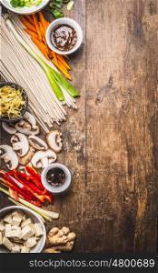 Various asian cuisine ingredients with tofu, noodles , spices, vegetables and sauces for tasty vegetarian cooking on rustic wooden background, top view, place for text
