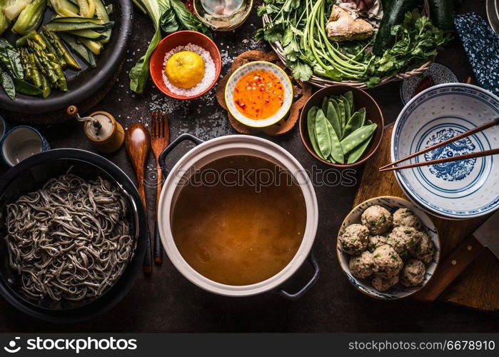 Various asian food ingredients for tasty soba noodles soup around cooking pot with delicious miso broth or stock on rustic kitchen table background, top view. Asian cuisine background. Healthy eating