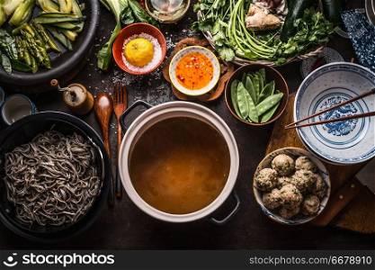 Various asian food ingredients for tasty soba noodles soup around cooking pot with delicious miso broth or stock on rustic kitchen table background, top view. Asian cuisine background. Healthy eating
