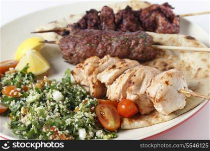 Various barbecued kebabs - kofta, chicken tawook and sumac chicken - with tabouleh and pitta bread; an Arab or Lebanese-style feast.