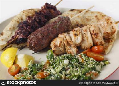 Various barbecued kebabs - kofta, chicken tawook and sumac chicken - with tabouleh and pitta bread; an Arab or Lebanese-style feast,
