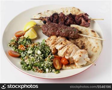 Various barbecued kebabs - kofta, chicken tawook and sumac chicken - with tabouleh and pitta bread; an Arab or Lebanese-style feast.