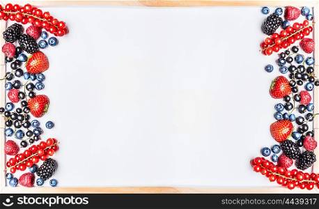 Various berries on white chalkboard background, top view, frame