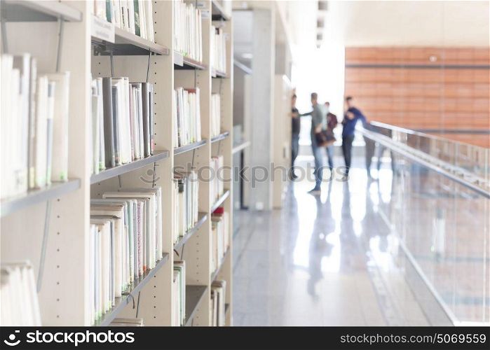 Various books arranged on shelf at corridor in university library