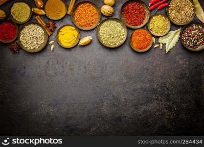 Various bowls of spices over dark background - flat lay