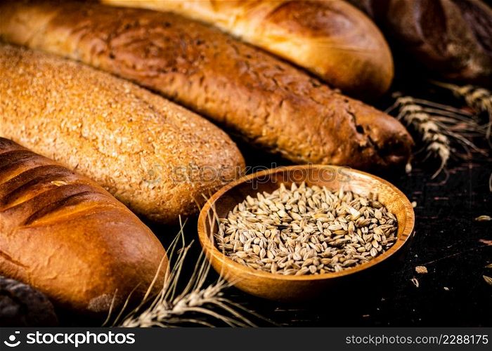Various bread with grain in a bowl on the table. Against a dark background. High quality photo. Various bread with grain in a bowl on the table.