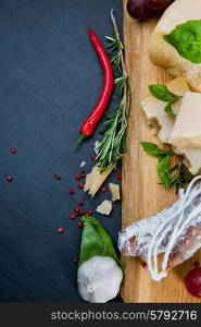 Various cheeses and salami on the wooden board