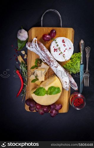 Various cheeses and salami on the wooden board