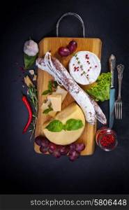 Various cheeses and salami on the wooden board