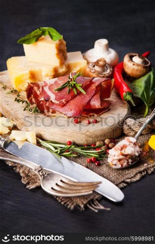 Various cheeses, salami and mushrooms on the wooden board