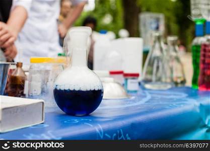 Various chemical utensils on the table. In front is a flask in which a chemical reaction. Scientific chemical experiments