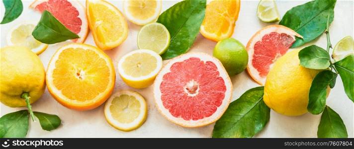 Various citrus fruits background banner with halves, slices and green leaves. Top view. Vitamin C. Healthy natural immun boosters. Refreshing ingredients for drinks