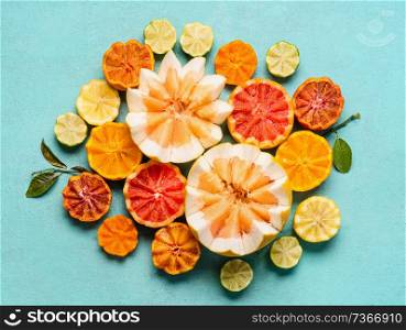Various citrus fruits on light blue background, top view. Composing with half of orange fruits, lemon, grapefruit, mandarin, lime, clementines, pomelo and blood orange. Flat lay. Healthy food