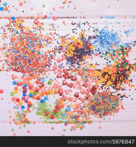 Various color sprinkles scattered on white wooden table. color sprinkles