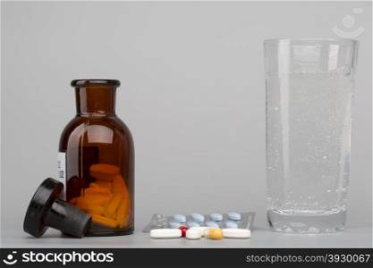 Various colored pills,medical bottle and glass of water