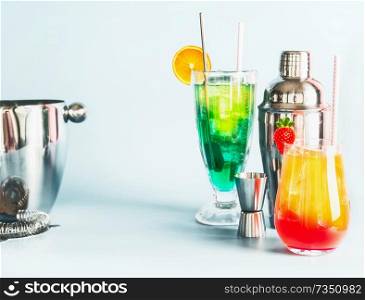 Various colorful long drinks and cocktails bar tools at light blue background, copy space. Summer alcoholic beverages