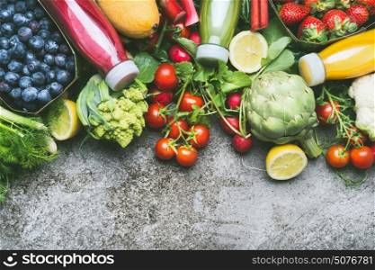 Various colorful smoothie and juices in bottles with fresh organic vegetables and fruits on grey concrete background, top view, border
