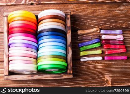 Various colors ribbon bobbins in vintage wooden box. Colorful ribbon bobbins on the wooden table