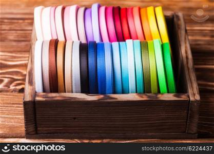 Various colors ribbon bobbins in vintage wooden box. ribbon bobbins in box