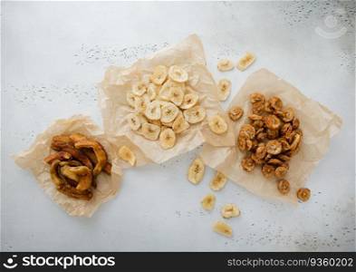 Various crunchy and chewy banana slices and chips snack on light board.Top view.