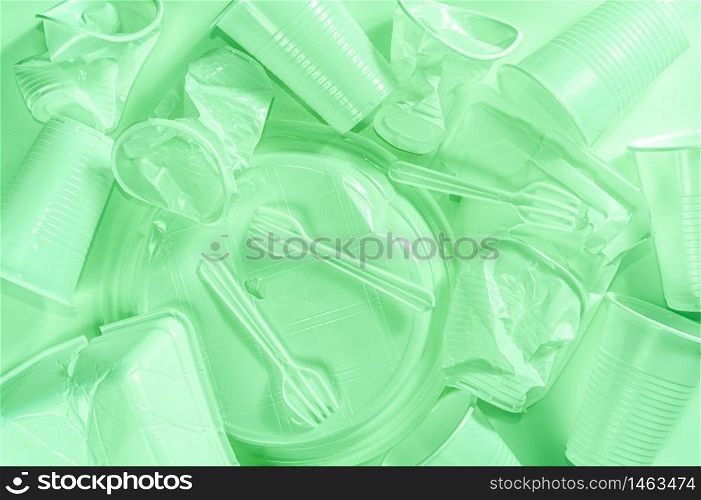 Various disposable plastic tableware, cutlery on a light background in pastel colors. Minimalistic ecologically clean still life. Pop Art. And ecology problem concept. Toned green.. Disposable plastic tableware on a light background in pastel colors. Minimalistic ecologically clean still life. Pop Art. And ecology problem concept.
