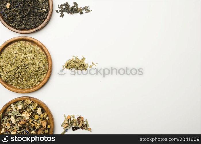 various dried herbs wooden plates against white background