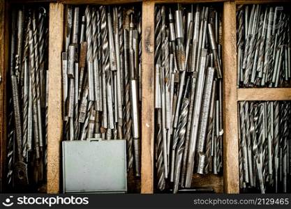 Various drill bits for drills. On a wooden background. High quality photo. Various drill bits for drills.