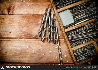 Various drill bits for drills. On a wooden background. High quality photo. Various drill bits for drills.