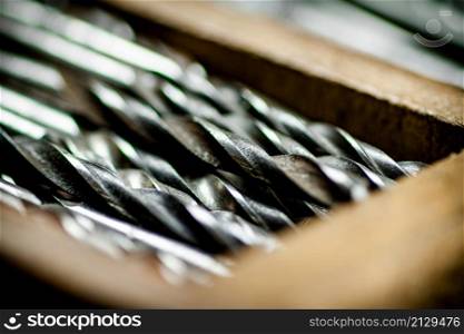 Various drill bits for drills. On a wooden background. High quality photo. Various drill bits for drills.