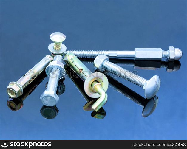 Various equipment: screw bolts and bolts with washers on a glossy dark blue surface of a metal background design.. Screwbolts screw nuts, hanger and bolt washers on blue background construction concept.