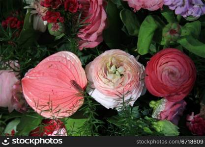 Various flowers in different shades of pink and red in a flower arrangement