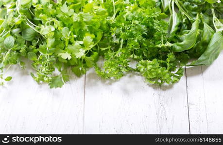 various fresh green herbs on a wooden table